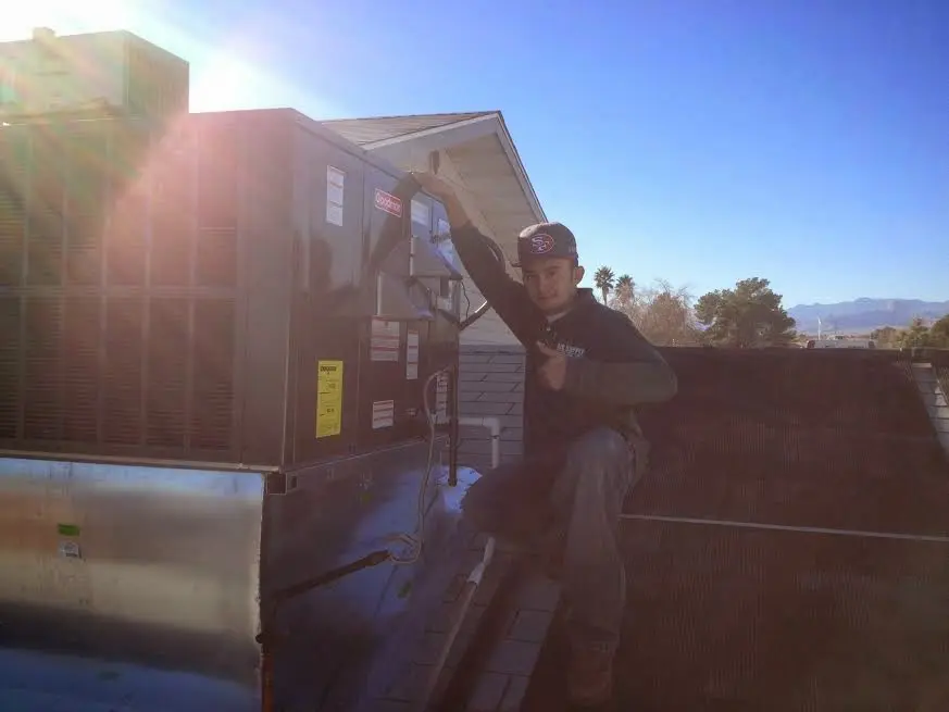 HVAC technician performing Air Duct Repair on a rooftop unit in Glenwood